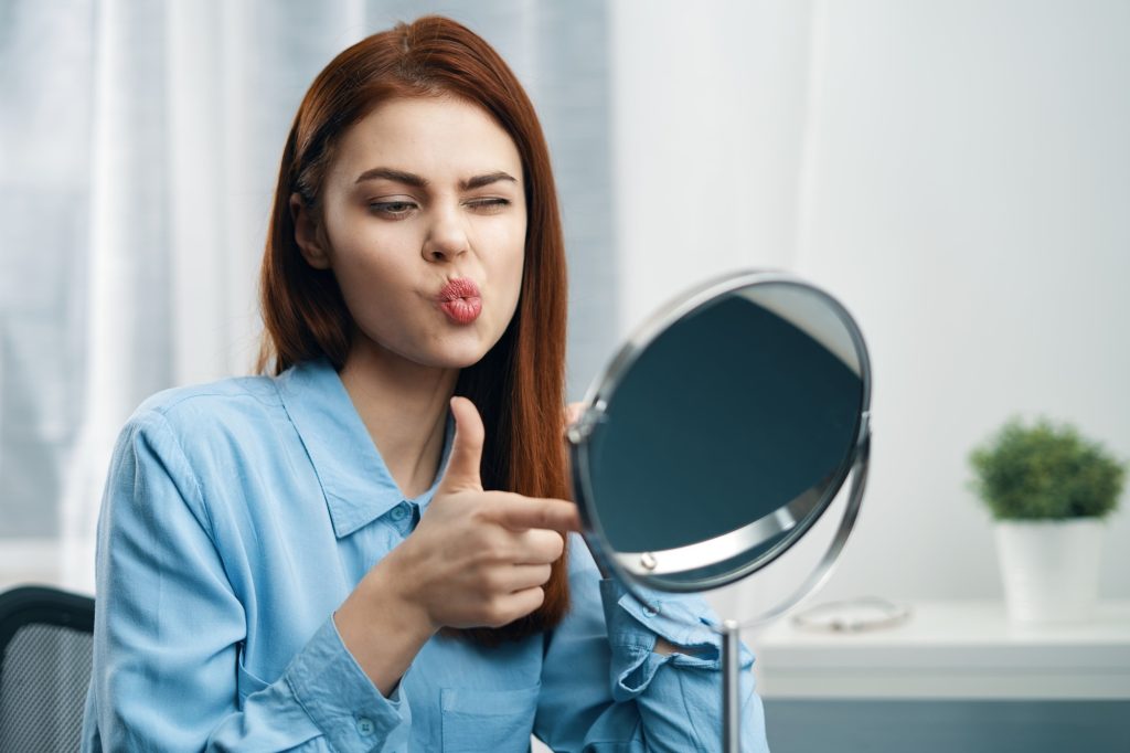 woman looking in the mirror cosmetics personal care