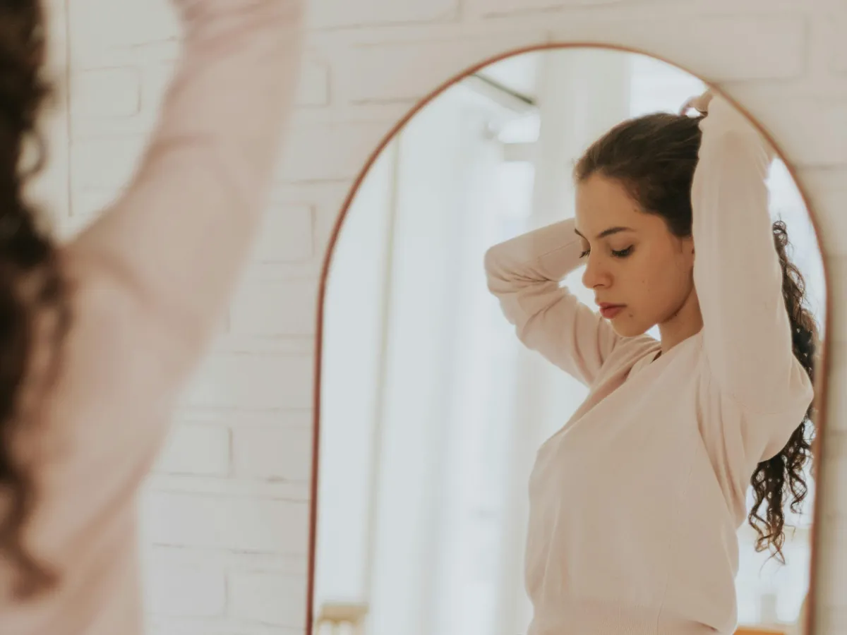 Mujer mirándose al espejo con calma, trabajando su autoimagen