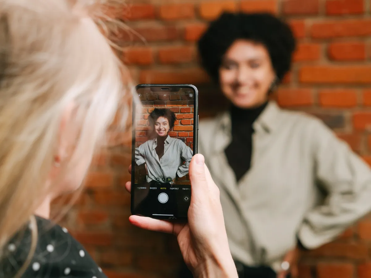 Mujer sonriendo mientras la fotografían con el móvil
